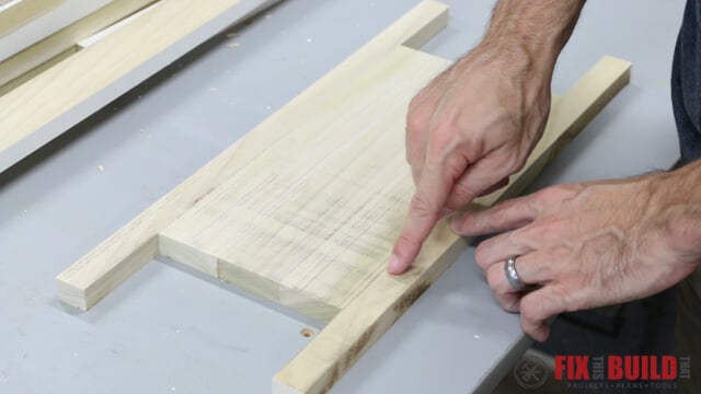 Sacrificial side runners glued along the edges of a wood glue-up to absorb planer snipe instead of the finished workpiece