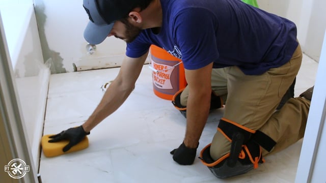 wiping excess grout off of tiles with a wet sponge