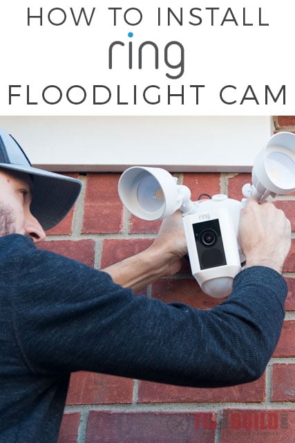a man installing the ring floodlight cam on an exterior red brick wall