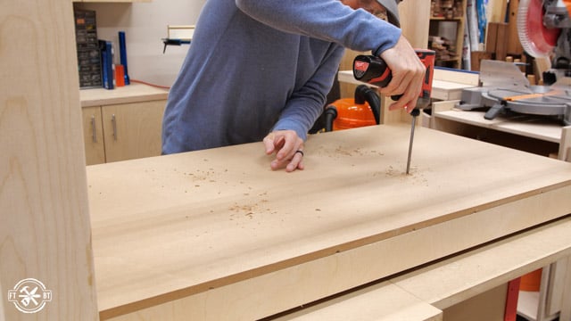 screwing lower shelf into place on table