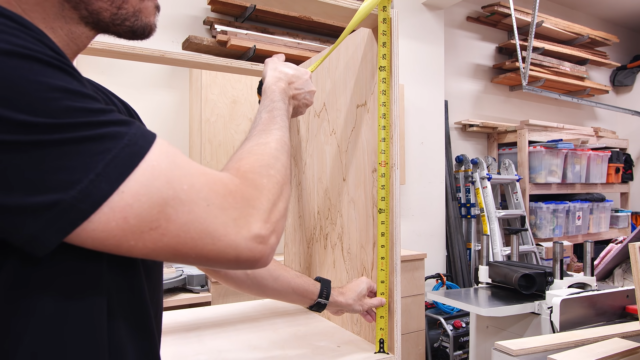 using measuring tape to measure opening in cabinet