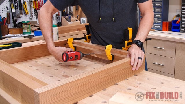screwing side supports into wooden seat base